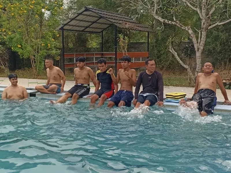 Siswa dan pendamping duduk berjajar di tepi kolam melatih gerak kaki bersama-sama